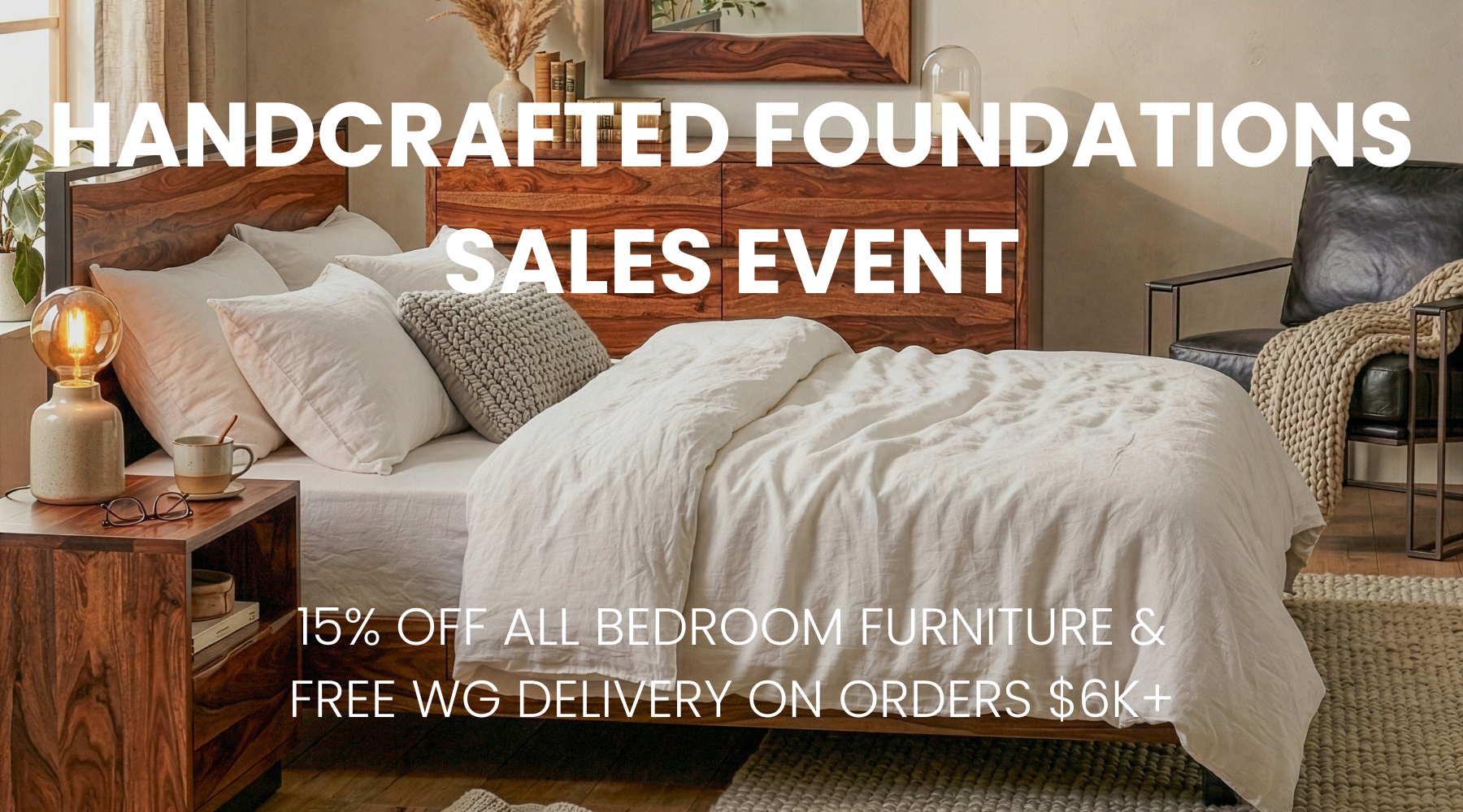 A styled bedroom scene with a wooden bed frame, white bedding, pillows, a bedside table with a lamp, and a chair in the background. Large overlaid text reads 'HANDCRAFTED FOUNDATIONS SALES EVENT' and '15% OFF ALL BEDROOM FURNITURE & FREE WG DELIVERY ON ORDERS $6K+'.